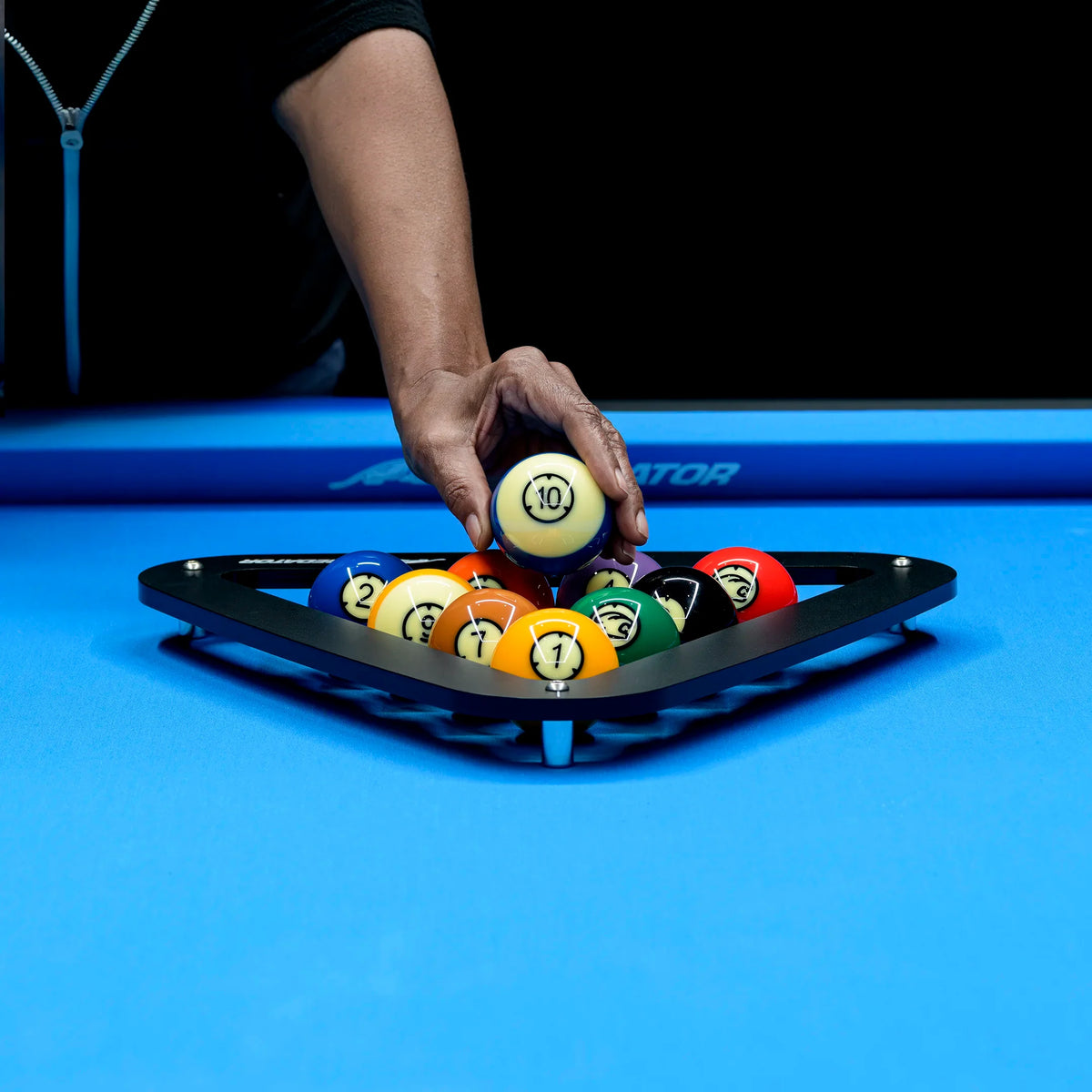 Person arranging pool balls on a blue pool table