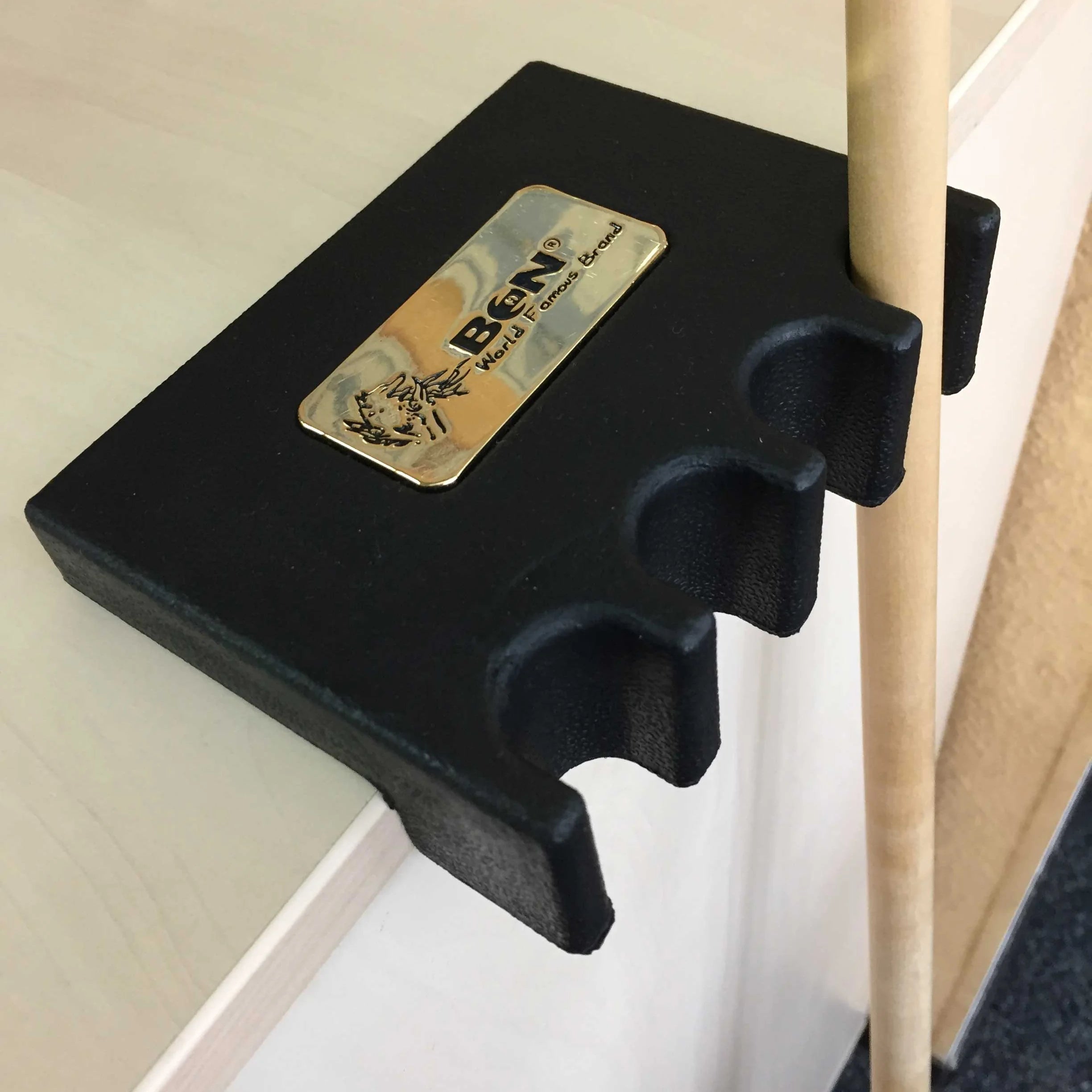 BCN Table-Edge Cue Holder In Black With A Gold BCN Badge And Three Cue Slots, Holding A Cue Upright Beside A Table