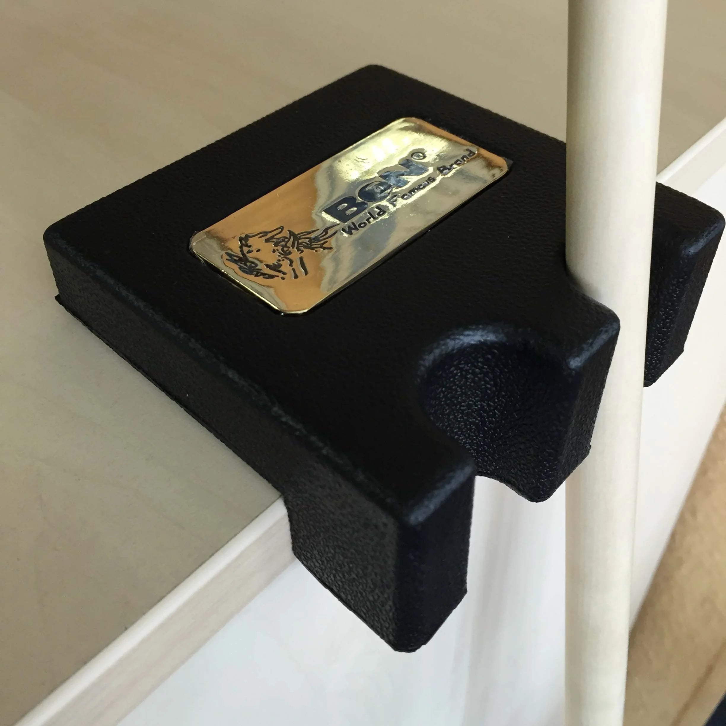 BCN Single-Slot Table-Edge Cue Holder In Black With A Gold BCN Badge, Clamped To A Table Edge And Holding A Cue